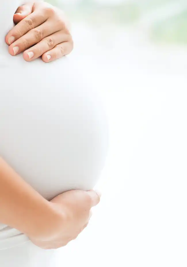 Babybauch einer schwangeren Frau, die ihre Hände darauf legt